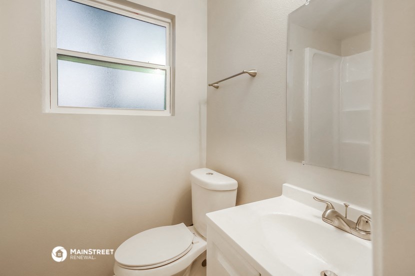 a bathroom with a toilet and a sink and a window