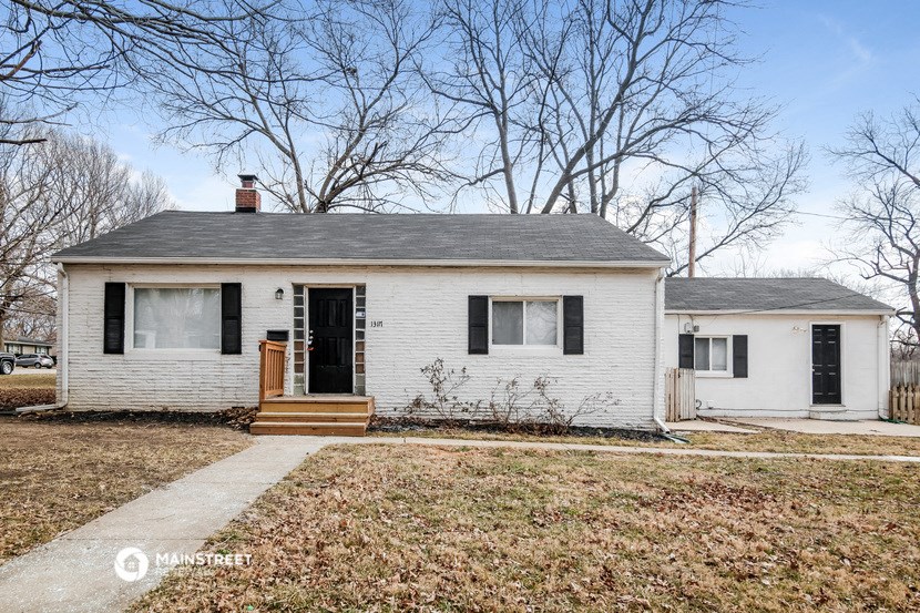 a small white house with black shutters and a front yard