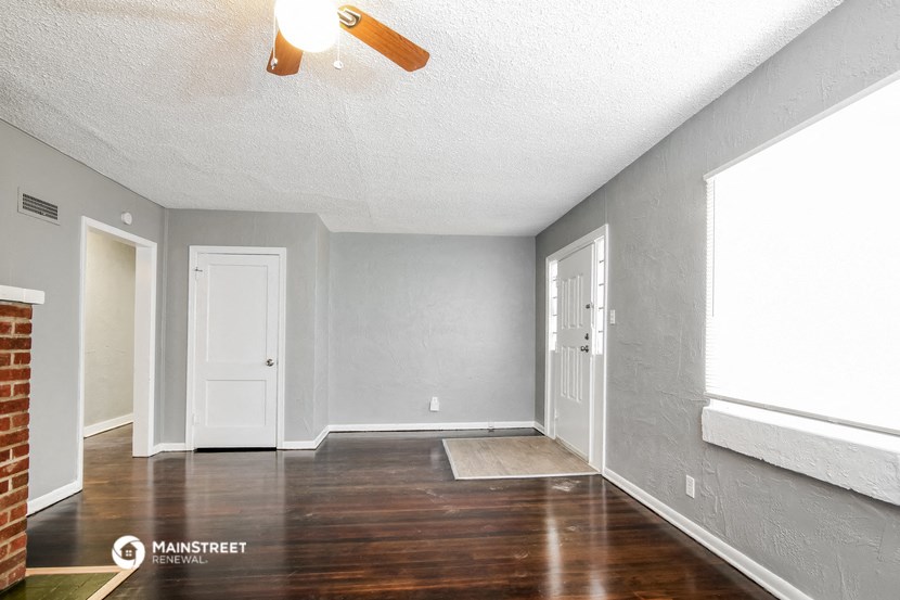 an empty living room with wood floors and a ceiling fan