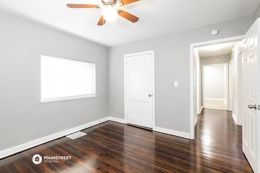 an empty room with wood floors and a ceiling fan