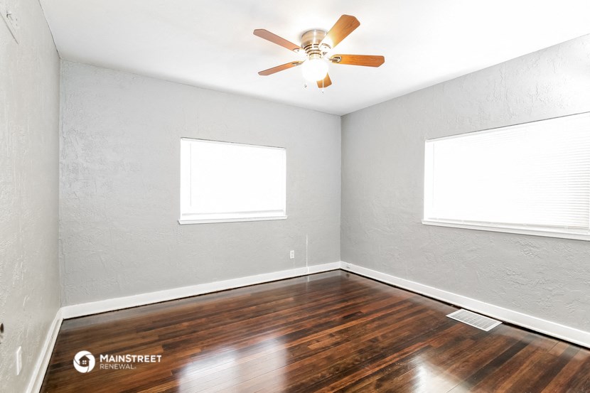 the living room with wood floors and a ceiling fan