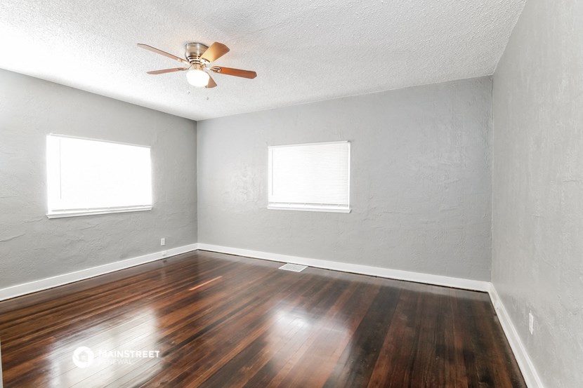 an empty room with wood floors and a ceiling fan