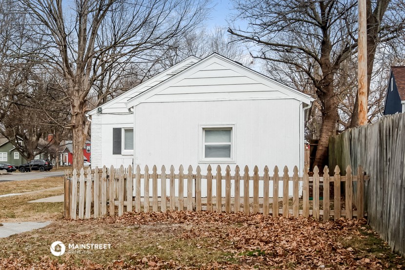 a small white house with a fence in front of it