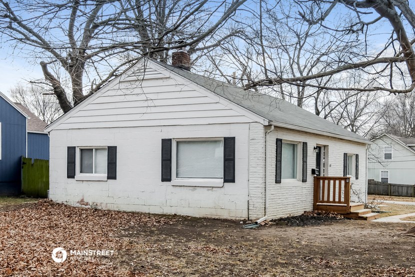 a small white house with black shutters and a porch