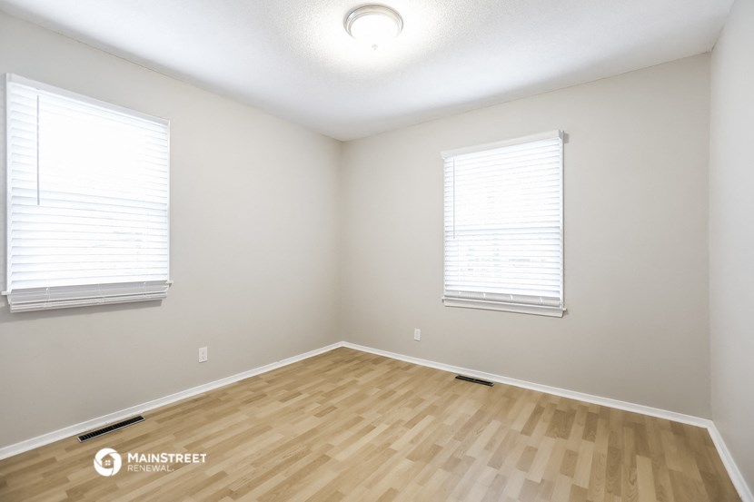 the spacious living room with wood flooring and two windows