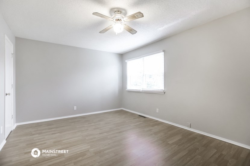an empty living room with a ceiling fan and a window