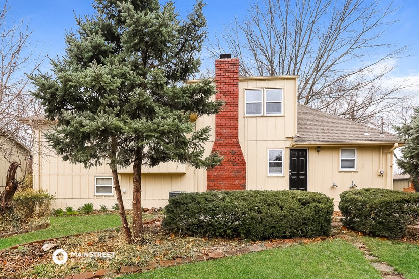 the front of a house with a yard and a tree