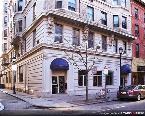 a white building on the corner of a street with a car