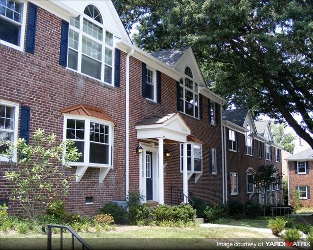 a red brick house with a tree in front of it