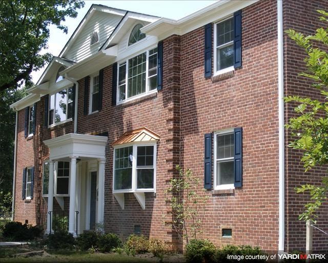 a red brick house with black shuttered windows