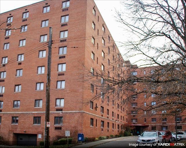 a tall brick building with cars parked in front of it