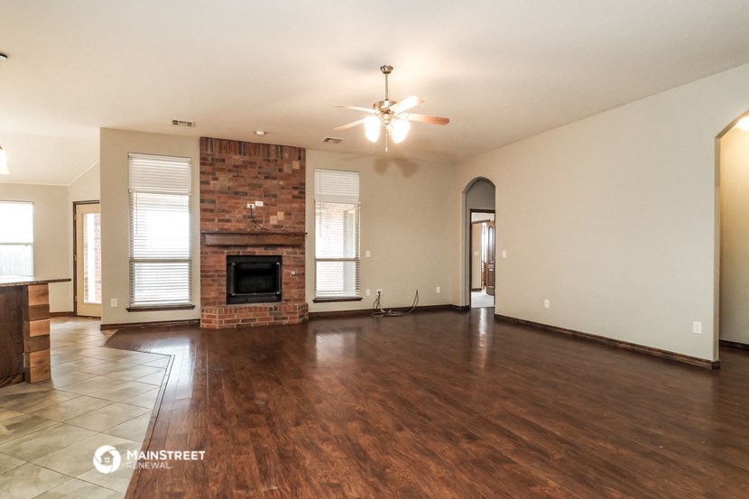 an empty living room with a fireplace and a ceiling fan