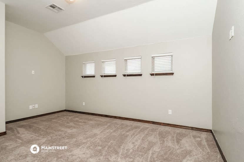 the living room is spacious and clean with white walls and carpet