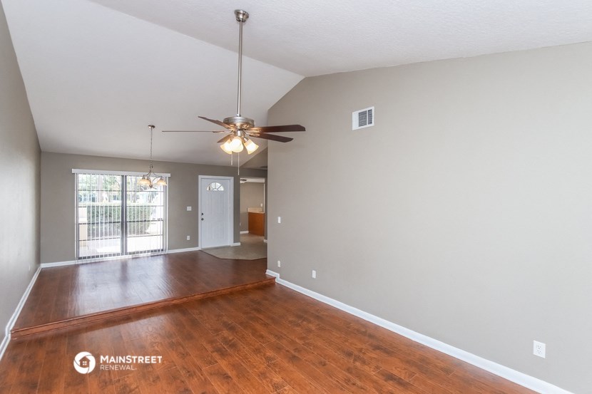 the living room and dining room with wood flooring and a ceiling fan