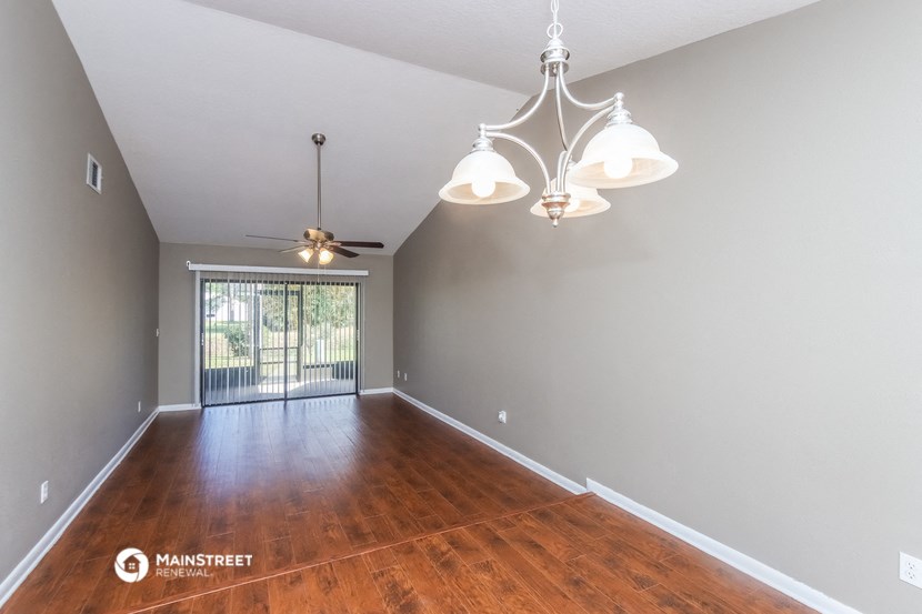 the spacious living room with hardwood flooring and ceiling fans