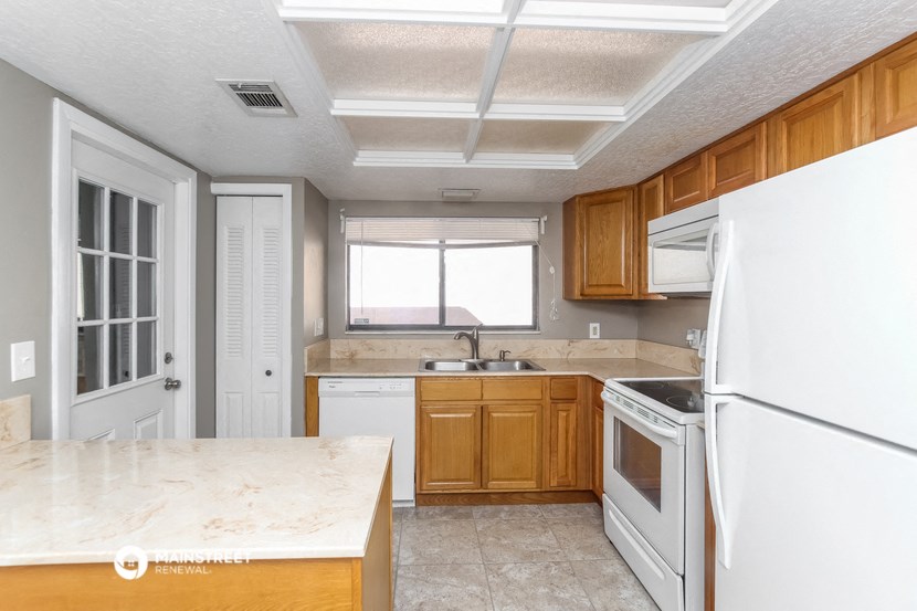 an empty kitchen with white appliances and wooden cabinets