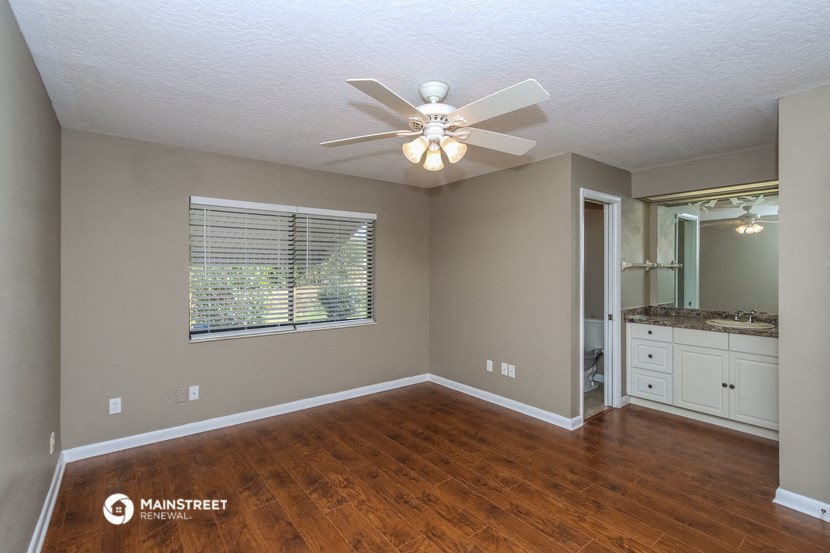 the spacious living room with hardwood flooring and a ceiling fan