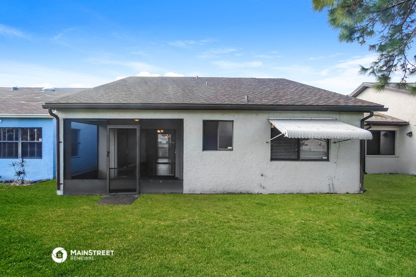 a small white house with a yard and a blue door