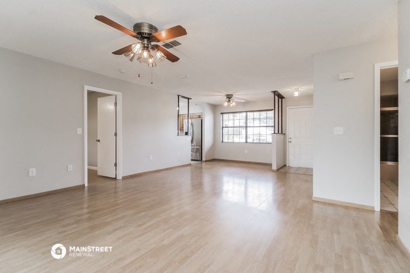 the living room and dining room of an empty house with a ceiling fan