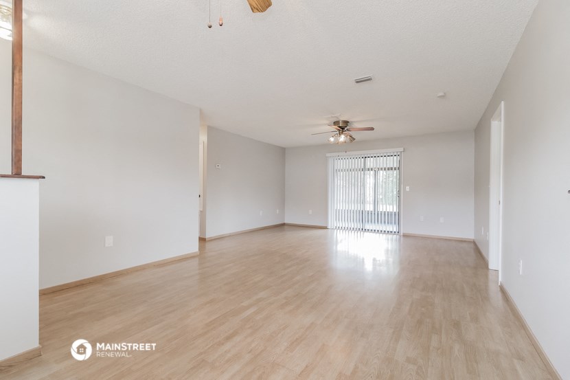 a spacious living room with wood flooring and a ceiling fan