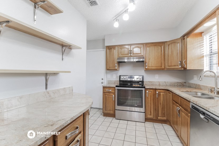 a kitchen with wooden cabinets and marble counter tops and a stove top oven