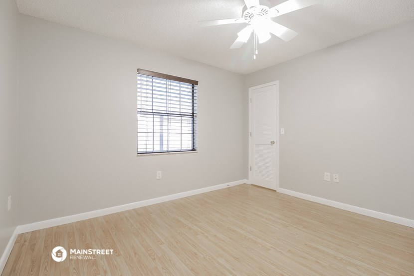 the spacious living room with hardwood floors and a ceiling fan