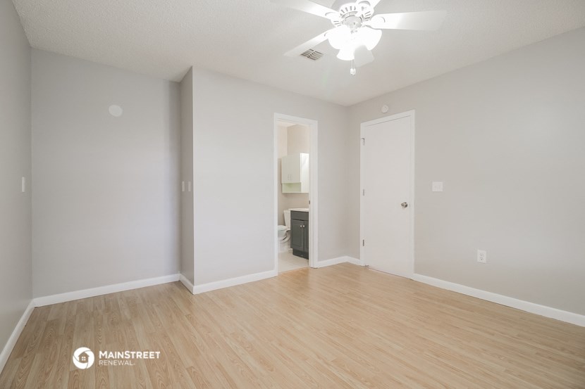 a spacious living room with wood flooring and a ceiling fan