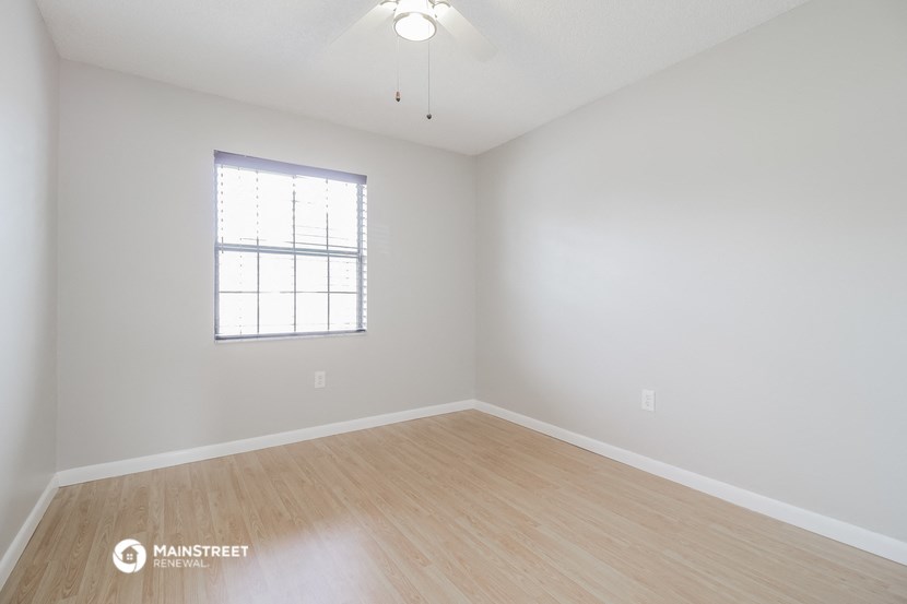the spacious living room with hardwood floors and a window