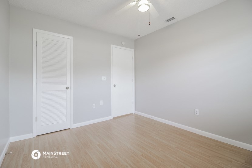 the spacious living room with wood flooring and white walls