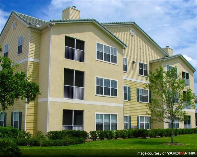a yellow apartment building with a green lawn