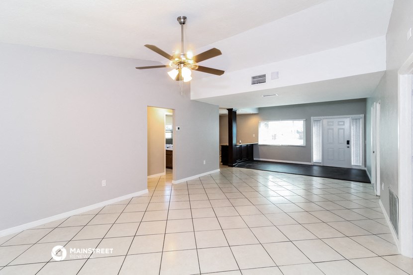 an empty living room with tile flooring and a ceiling fan