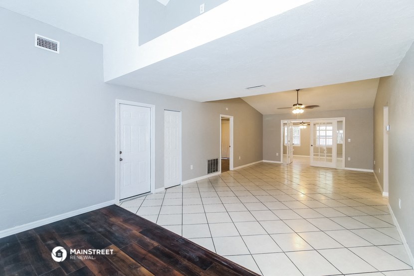 an empty living room with a white tile floor and a ceiling