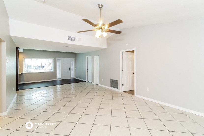 an empty living room with a ceiling fan and a tiled floor