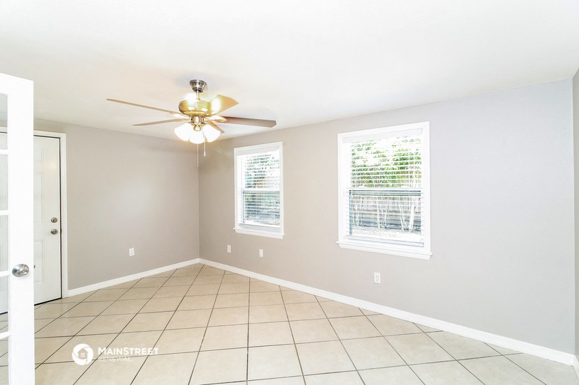 an empty living room with a ceiling fan and a tiled floor