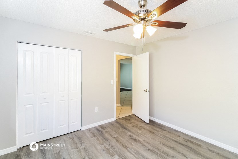 a bedroom with a ceiling fan and a door to a closet