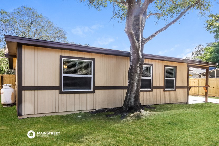 the exterior of a tan house with a tree in the yard