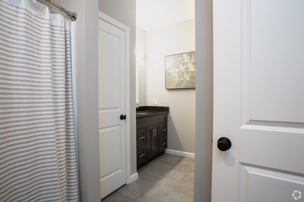 a bathroom with a shower and a black vanity with a white shower curtain