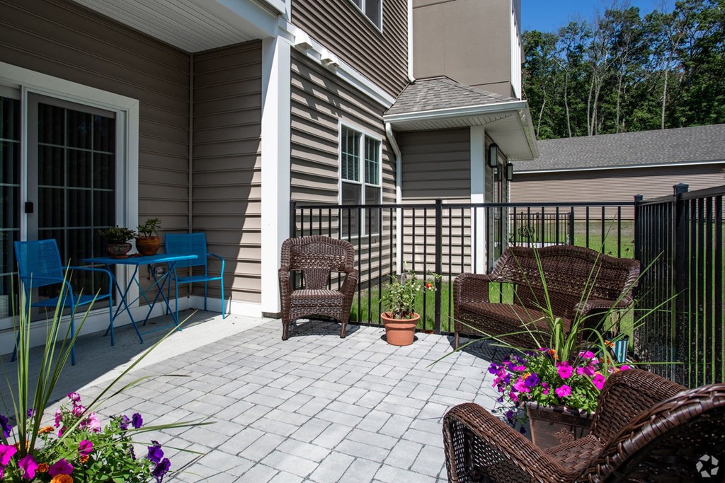 a patio with chairs and a table in front of a house