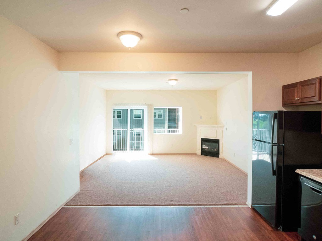 an empty living room with a black refrigerator and