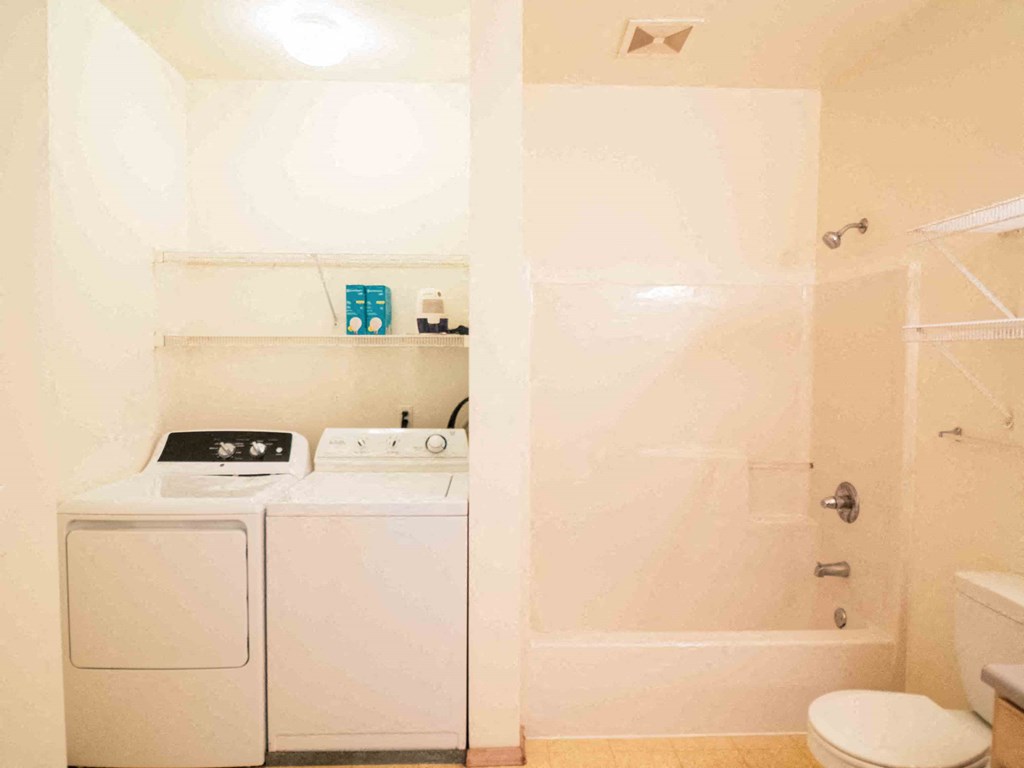 a bathroom with a washer and dryer and a shower and a sink