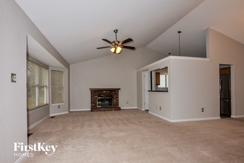A spacious living room with a fireplace and a ceiling fan.