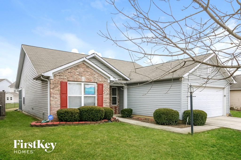 a small brick house with a red door and a lawn