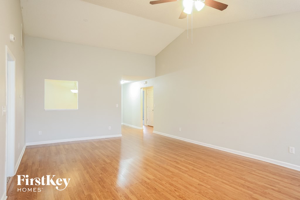 an empty living room with wood floors and a ceiling fan