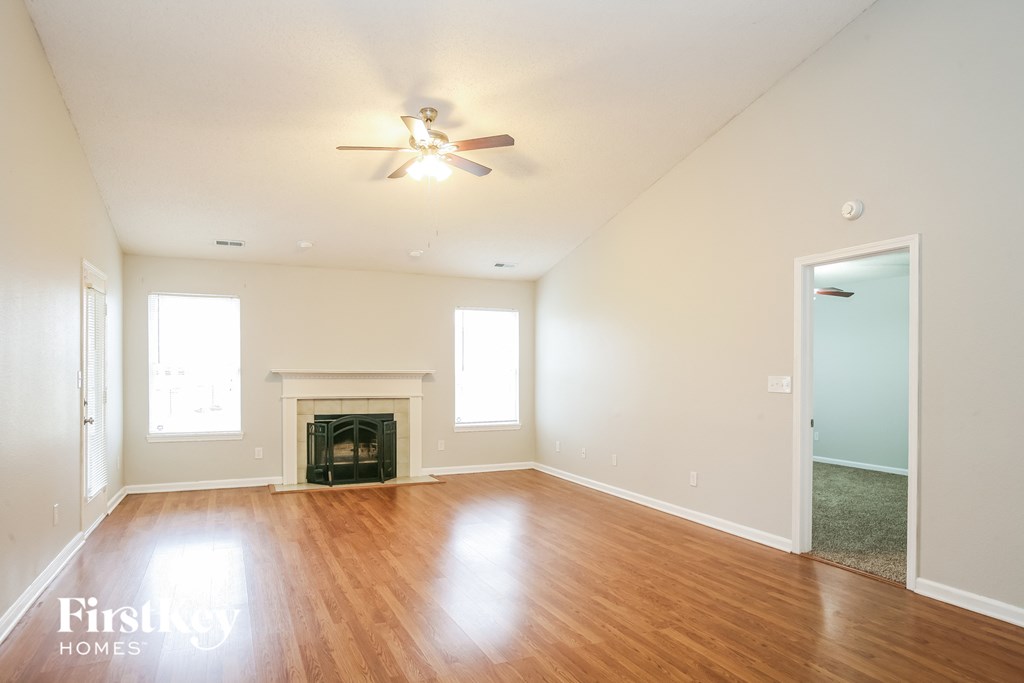 an empty living room with a ceiling fan and a fireplace