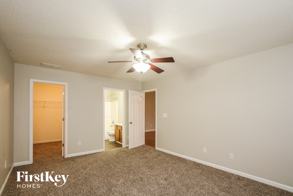 the spacious living room with ceiling fan and carpeting