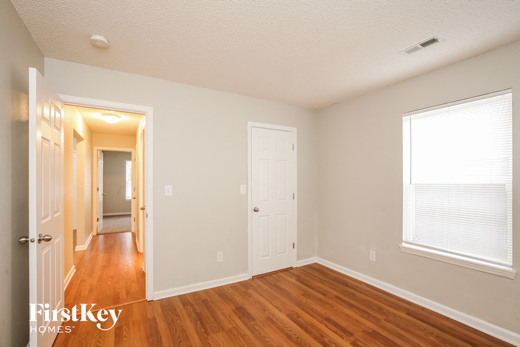 a bedroom with a hard wood floor and a door to a hallway