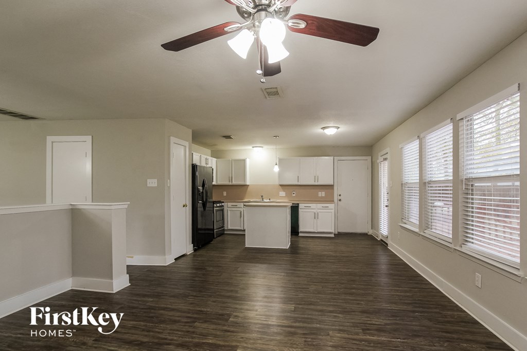 an empty living room and kitchen with a ceiling fan