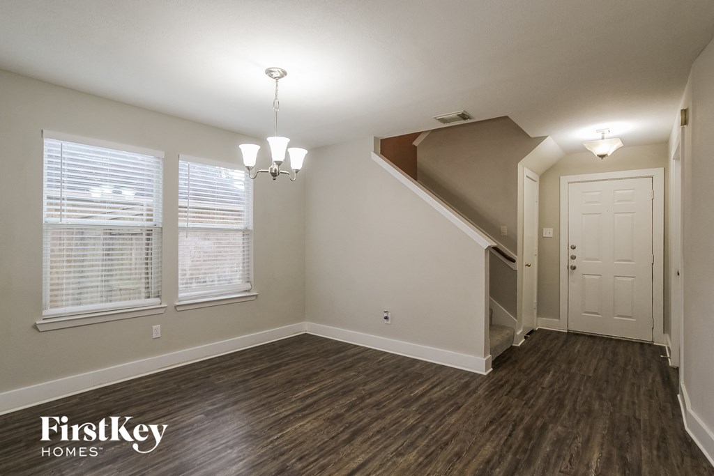 an empty living room with wood flooring and a staircase