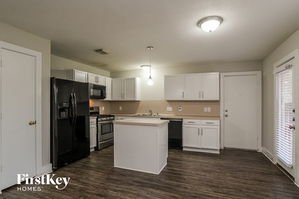 an empty kitchen with white cabinets and a black refrigerator