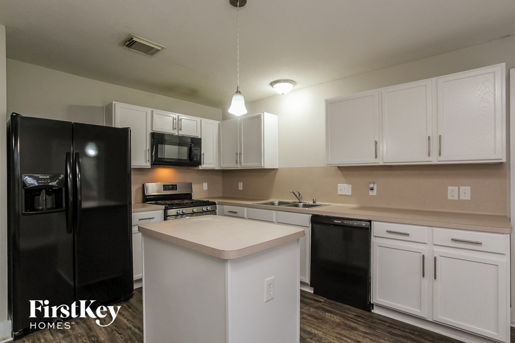an updated kitchen with white cabinets and black appliances